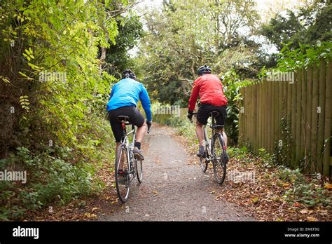 Two Mature Male Cyclists Riding Bikes Along Path Stock Photo Alamy