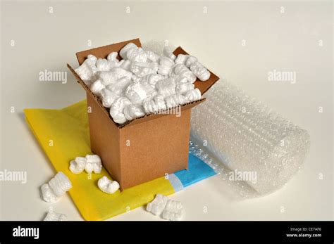 A Brown Cardboard Box Sits On Top Of Tissue Paper With Shipping Peanuts Spilling Out With Bubble