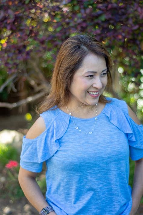 M E De Latina Que Sorri No P Tio Traseiro Na Frente Do Arbusto Folhas Vermelho Foto De Stock