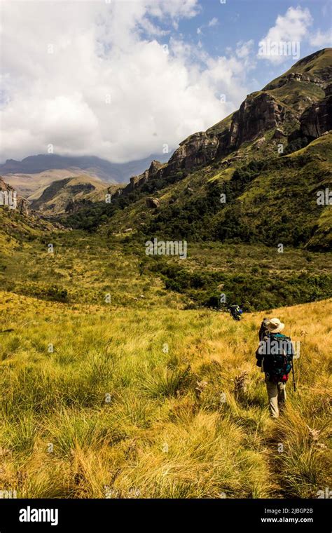 Hikers Walking In The Drakensberg Mountains With The High Peaks In The