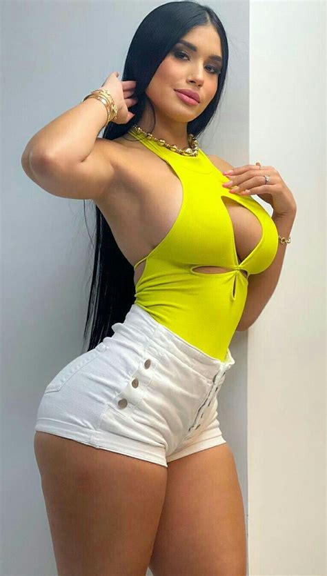 A Woman In Yellow Top And White Shorts Posing For The Camera With Her