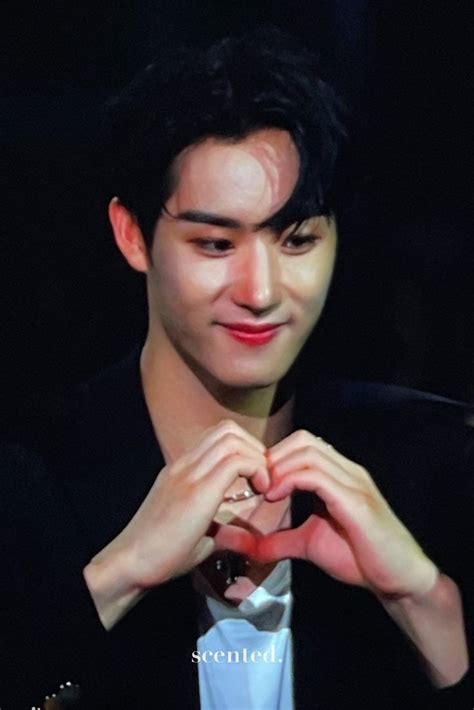 A Man Making A Heart With His Hands While Wearing A Black Jacket And