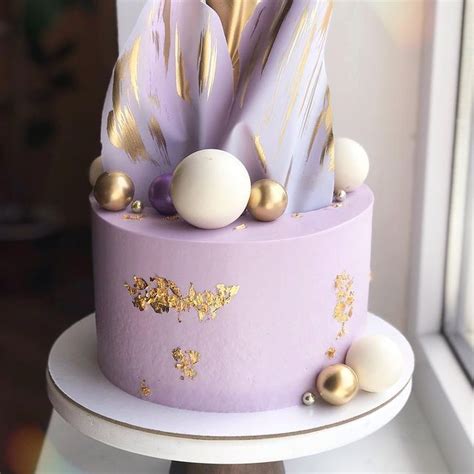 A Purple Cake With Gold Decorations On Top Sitting In Front Of A Window