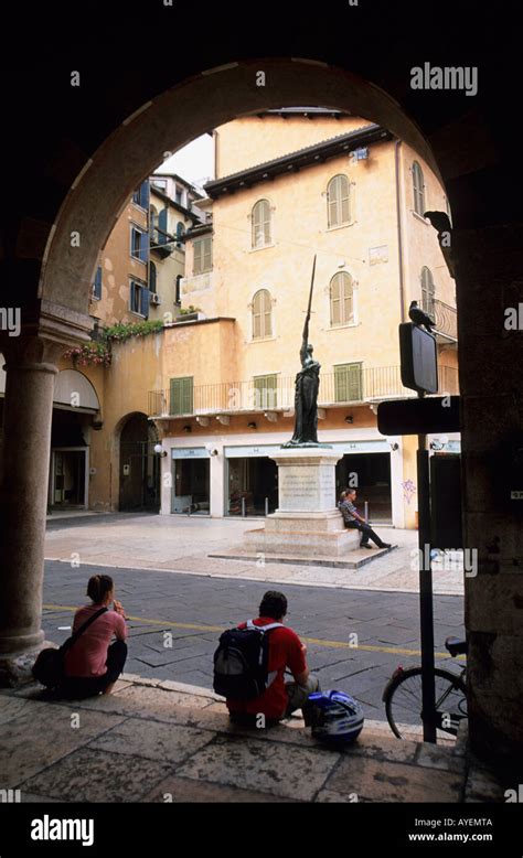 People Seated In One Of The Archways Of The Casa Dei Mercanti Piazza