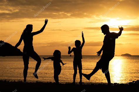 Silueta de familia feliz que juega en la playa al atardecer fotografía