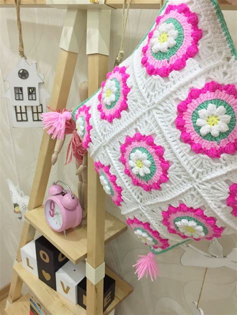 A Crocheted Pillow Hanging On A Ladder With Pink And White Flowers In