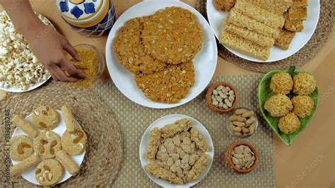 Hands Of An Indian Woman Placing Bhujia Chikki In A Glass Bowl For