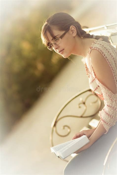 Chica Joven Que Lee La Biblia En Un Banco De Parque Foto De Archivo