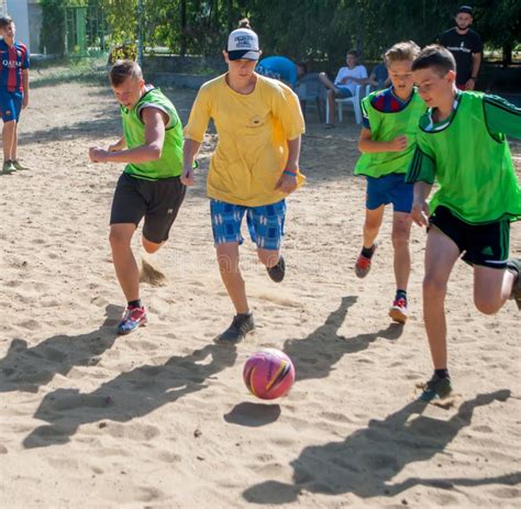 Soccer Boys Running For The Ball On A Sandy Field In A Summer Camp