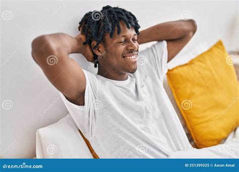 African American Man Relaxed With Hands On Head Sitting On Bed At