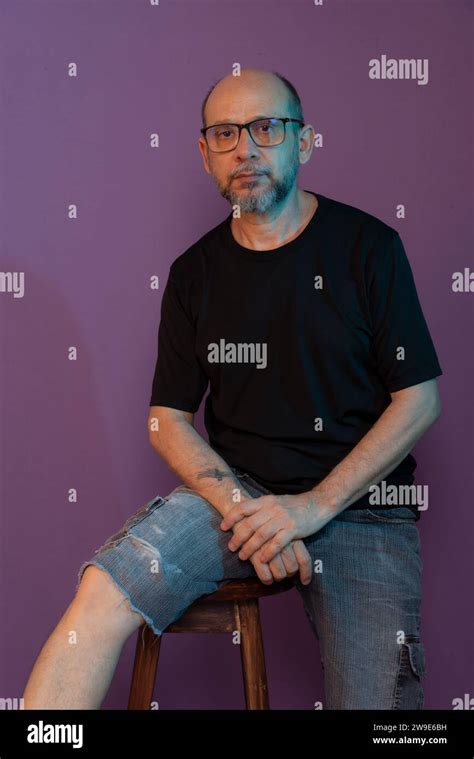 Bearded Bald White Man Wearing Prescription Glasses Sitting On Wooden