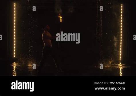 The Fakir Breathes Fire In A Dark Studio In The Rain A Silhouette Of A Half Naked Man Looms
