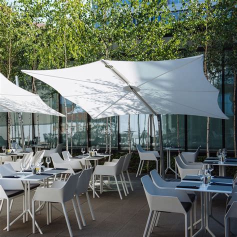 An Outdoor Dining Area With Tables And Chairs Under White Umbrellas On