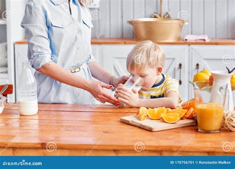 The Boy Drinks Milk From A Glass Mother And Son Are Smiling While