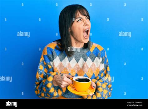 Young Hispanic Woman Drinking A Cup Of Coffee Angry And Mad Screaming