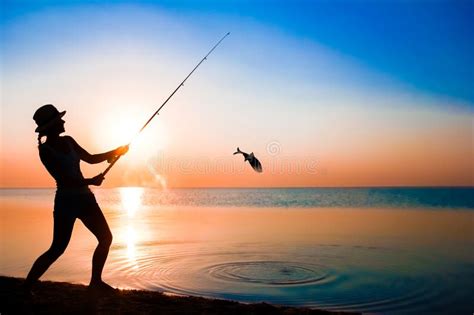 Uma Menina Pescadora Feliz Pega Peixe No Mar Na Silhueta Natural Imagem