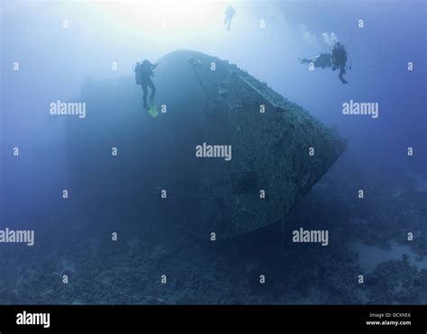 Scuba Divers Exploring A Large Sunken Underwater Shipwreck Stock Photo