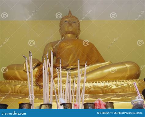 Burning Incense Sticks In Front Of A Gold Buddha Statue With Waving