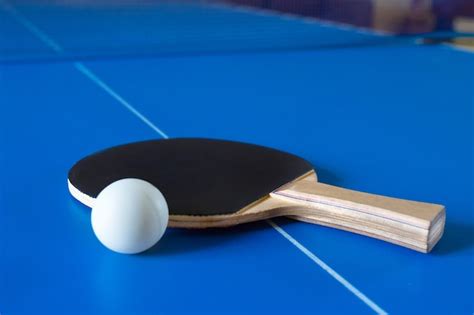 Raqueta De Madera Para Ping Pong Y Pelota Blanca Sobre La Mesa Azul