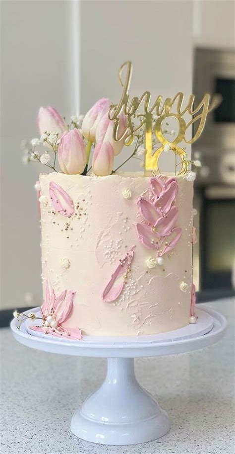 A Pink And Gold Birthday Cake With Flowers On Top