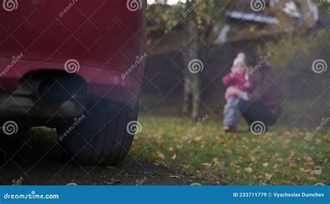 Mam Y Su Hija Juegan En Un Prado Cerca Del Cual Un Auto Que Fuma