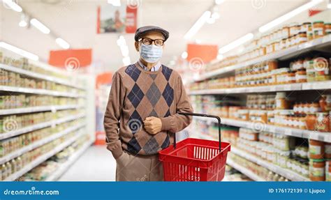 Senior Man Shopping In A Supermarket With A Medical Face Mask On Stock