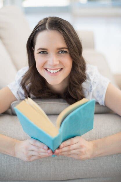 Premium Photo Smiling Pretty Woman Lying On A Cosy Couch Reading Book