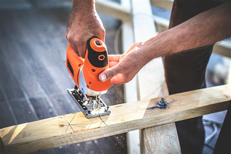 Carpenters Hand Using Electric Jigsaw To Cut Wooden Timber Stock Photo