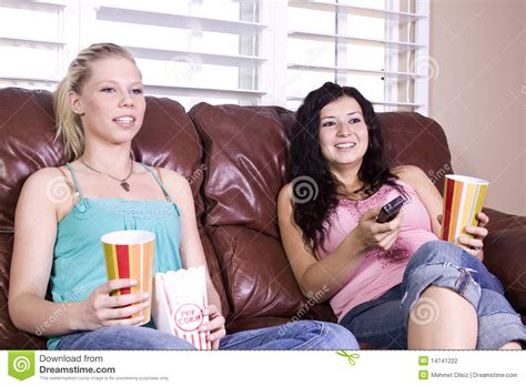 Deux Filles Sasseyant Sur Le Sofa Observant Un Film Photo Stock