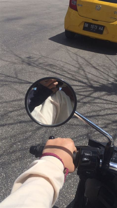 A Person Riding A Motorcycle With Their Hand On The Mirror