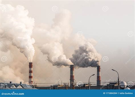 Industrial Chimneys With Heavy Smoke Causing Air Pollution On Gray Sky