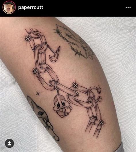 A Person With A Tattoo On Their Arm That Has Chains And Skulls Attached