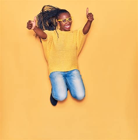 Jeune Belle Femme Afro Américaine Portant Des Vêtements Décontractés Et Des Lunettes Souriant