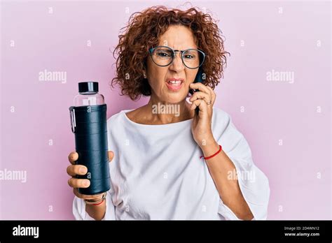 Beautiful Middle Age Mature Woman Using Smartphone Holding Water Bottle