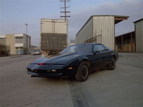 a black sports car parked in front of a building on the side of the road