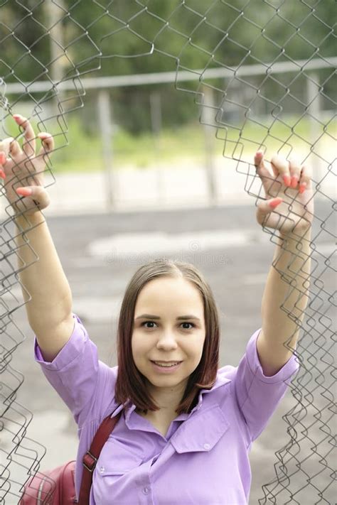 Young Woman With Short Hair In Purple Shirt Posing Holding On To Bars