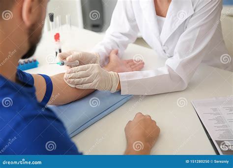 Female Doctor Preparing Patient For Blood Draw In Clinic Stock Photo