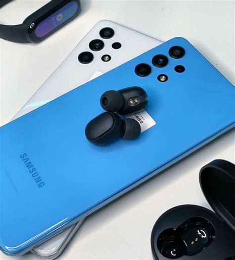 A Blue Samsung Phone Sitting On Top Of A Table Next To Ear Buds And