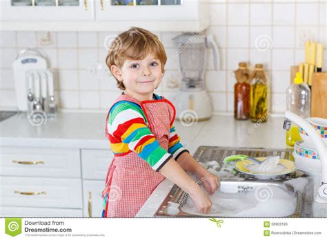 Gelukkige Weinig Blonde Wasschotels Van De Jong Geitjejongen In Binnenlandse Keuken Stock Foto