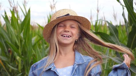 Happy Small Girl Looking Into Camera And Straightening Her Long Blonde Hair Against The