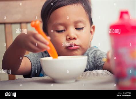 A Young Latino Boy Learning To Eat Independently With A Spoon In Hand