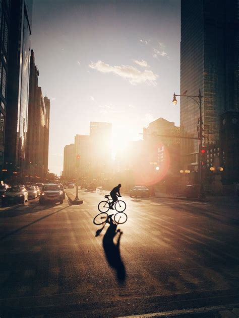 A Person Riding A Bike Down A Street Next To Tall Buildings And Traffic