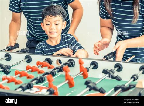 Niño feliz jugando futbolito fútbol de mesa con la familia el padre y