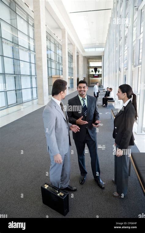 Three business people talking in the office hallway Stock Photo - Alamy