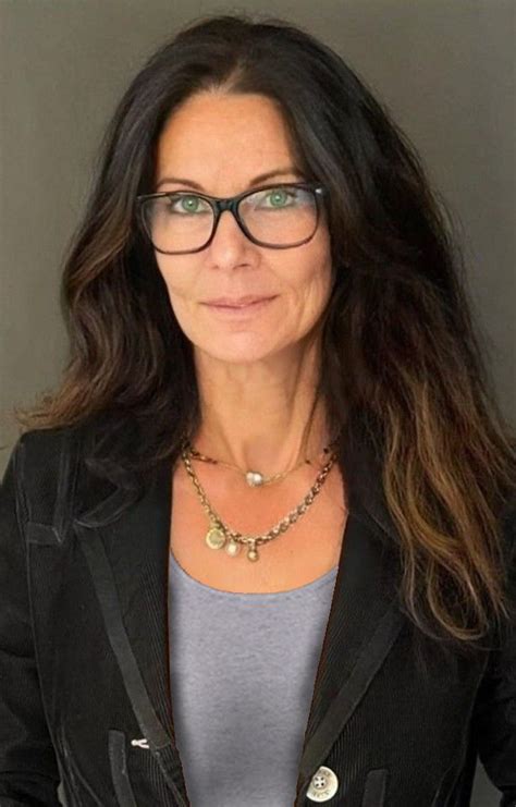 An Older Woman With Glasses Is Posing For The Camera Wearing A Black