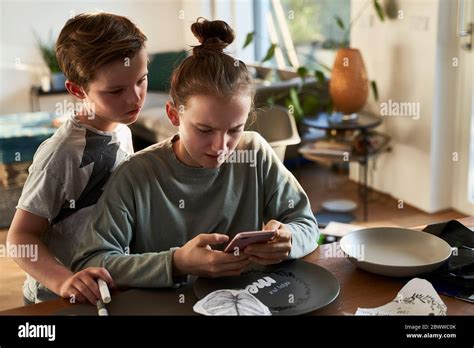 Brother And Sister At Home Using Smartphone For A Creative Online