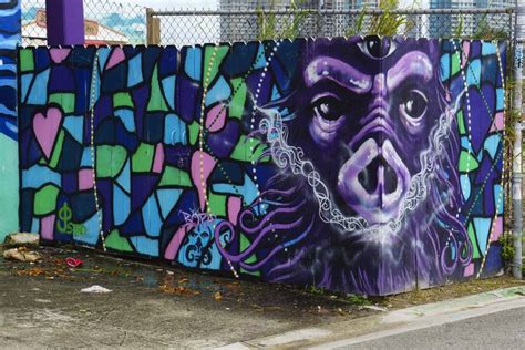 A Fence With Graffiti On It Next To A Wall Covered In Purple And Blue Tiles