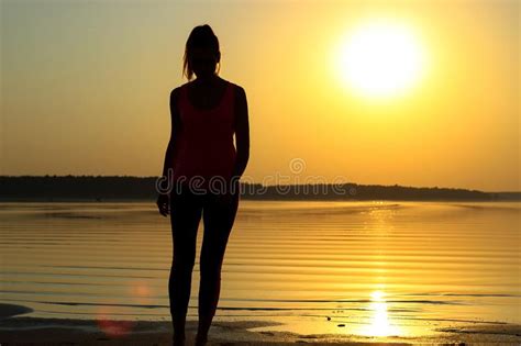 Silhouette of a Young Beautiful Girl Walking Along the Seashore during ...