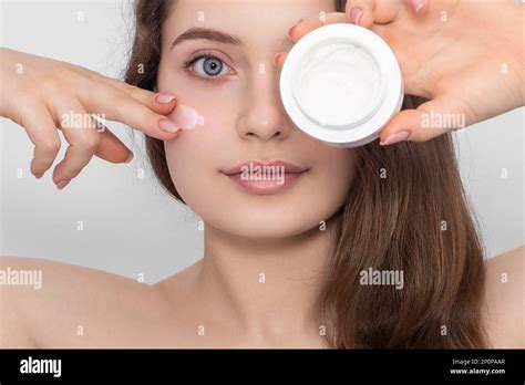 Young Beautiful Woman Applies Cream To Her Face Close Up Long Hair