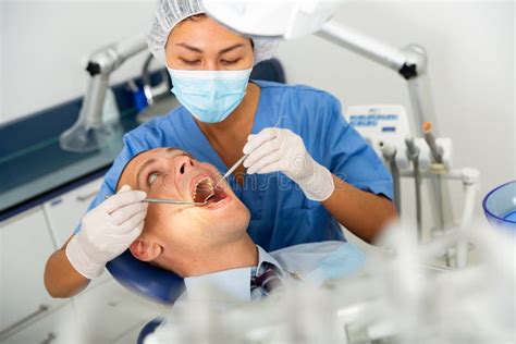 Female Dentist Examines The Oral Cavity Of Female Patient Dental